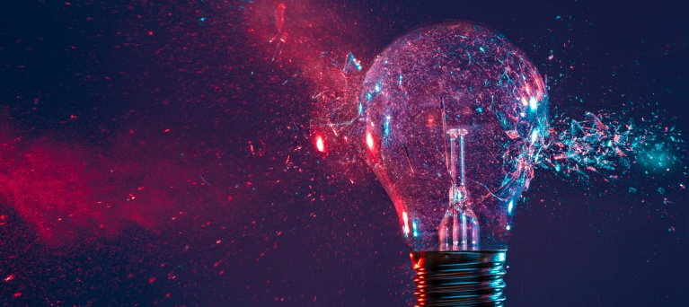 A light bulb being hit and exploding with pink and blue scatters.