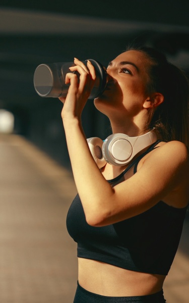 A young woman and man drinking protein shakes after their workout.