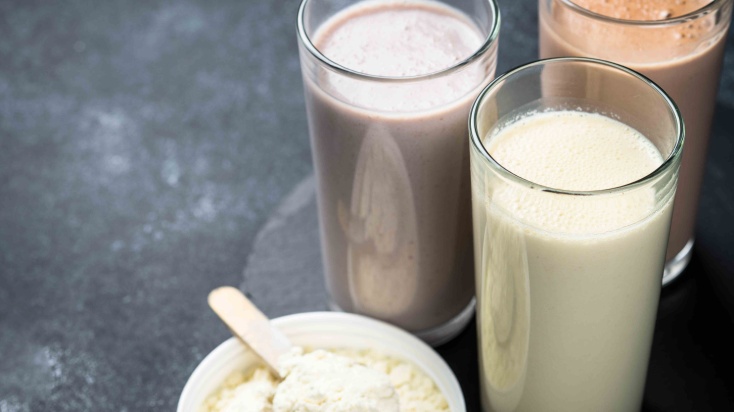 Three glasses of different types of milk shakes with protein powder.