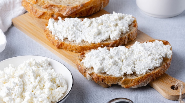 Crispy baguette with curd cheese on a wodden board.