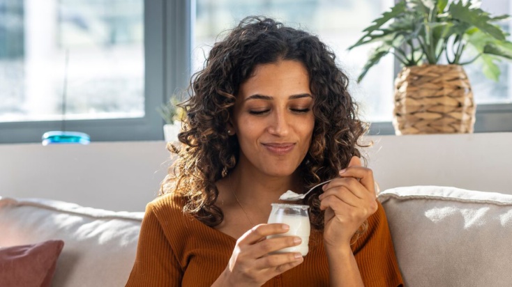 Woman on couch eating natural yoghurt