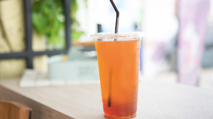 a cup of orange-red iced tea with a straw