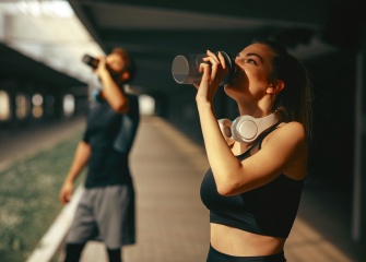 A young woman and man drinking protein shakes after their workout.