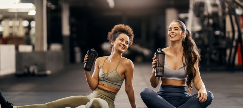 Two women in the gym enjoying the fitness break, both laughing. 