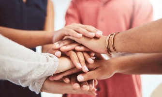 group a people putting their hands toghether in the middle.