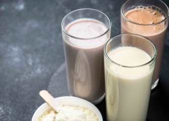 Three glasses of different types of milk shakes with protein powder.
